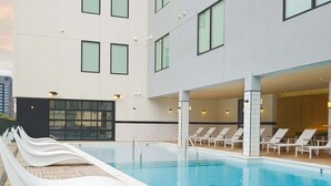 Ein Swimmingpool mit Rutsche, Liegestühlen und einem modernen Gebäude mit großen Fenstern.