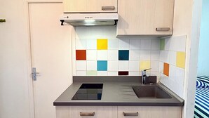 A small kitchen with a stove, sink, and cabinets.
