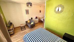 A room with a bed, a sofa, a small table, a desk, and a chair.