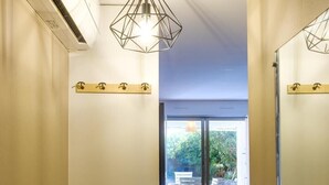 Un pasillo con un ventilador de techo, una lámpara, un banco de madera y vistas a un patio exterior.