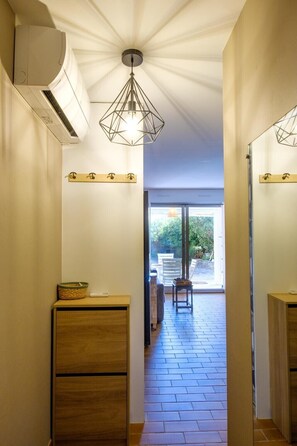 A hallway with a ceiling fan, a light fixture, a wooden bench, and a view of an outdoor patio. - Apartment facing the port, 50m from the beach (Roquebrune-sur-Argens)