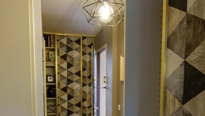 Un pasillo con paredes estampadas, una lámpara de diseño geométrico y una puerta con pomo.