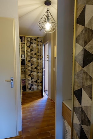A hallway with patterned walls, a geometric light fixture, and a door with a handle. - Apartment facing the port, 50m from the beach (Roquebrune-sur-Argens)
