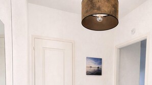 A hallway with a white door, a picture on the wall, and a black railing. - Charming apartment with terrace in Arès (Arès)