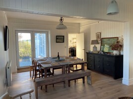 A dining area with a wooden table set for four, a bench, and a dark-colored cabinet with a lamp.