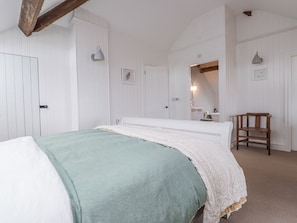 Un dormitorio con cama, una silla, un espejo y una puerta.