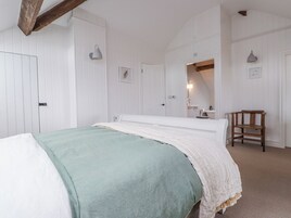 A bedroom with a bed, a chair, a mirror, and a door.