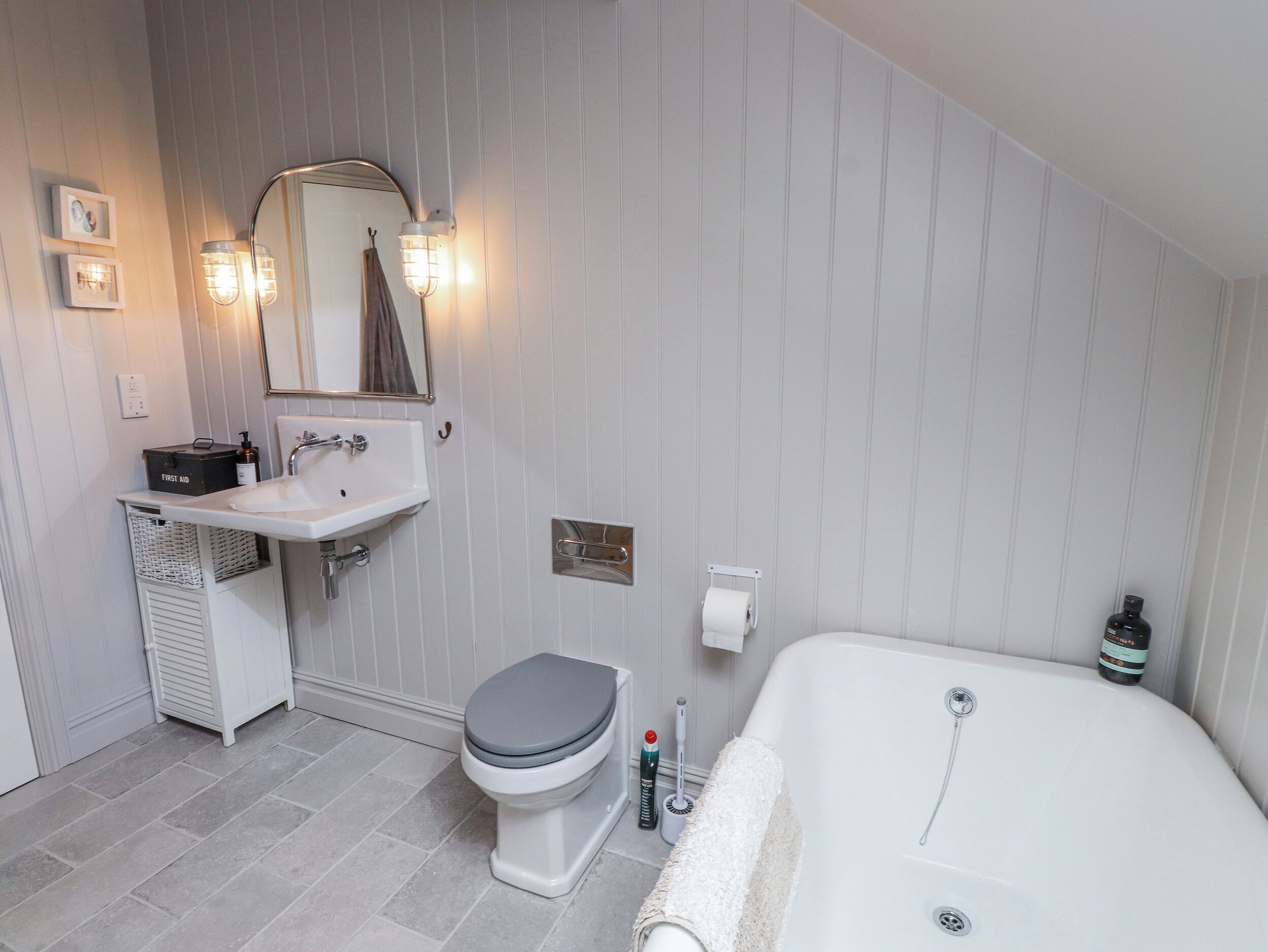 A bathroom with a white sink, toilet, and bathtub, a mirror, and a towel rack.