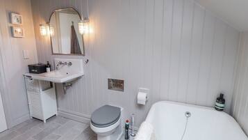 A bathroom with a white sink, toilet, and bathtub, a mirror, and a towel rack.