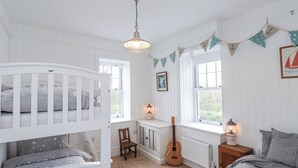 Ett rum med våningssängar, ett skrivbord, en gitarr och inredning med marint tema.
