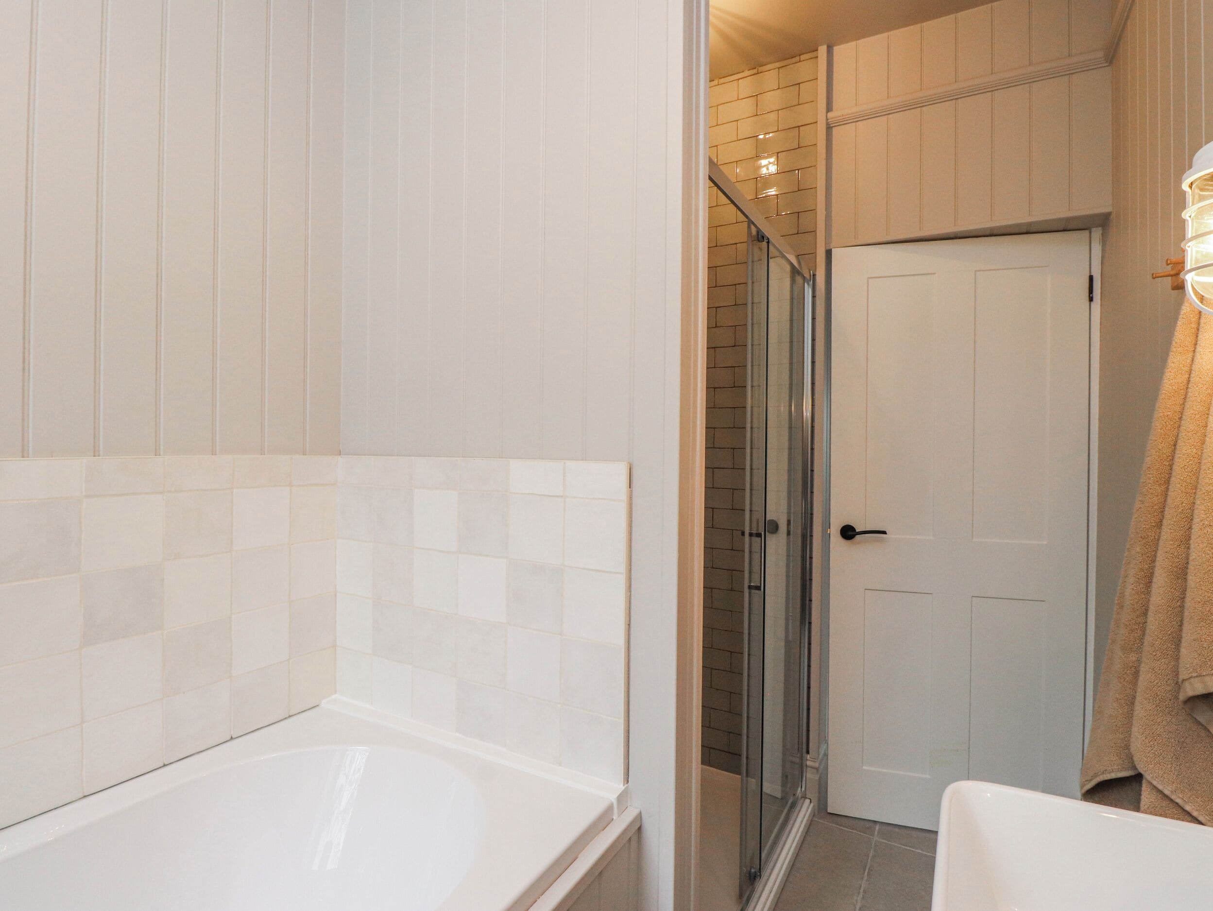Un baño con bañera, cabina de ducha de vidrio y una puerta blanca.