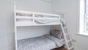 A bunk bed with a ladder, a window with a view, and a wooden floor.