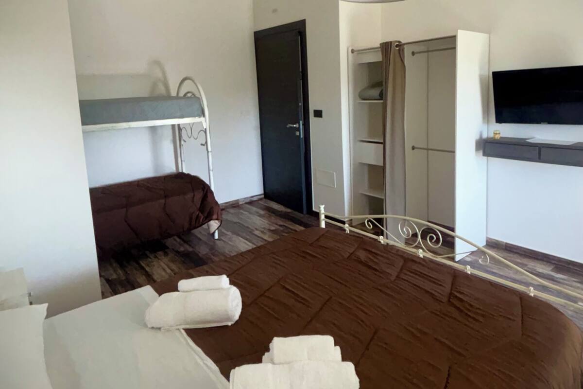 A hotel room with a large bed, a wardrobe, a television, and a shower area.