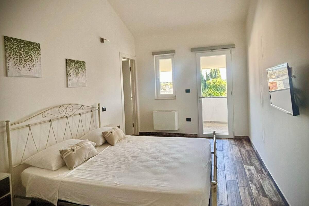 A bedroom with a bed, a radiator, and two windows.