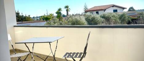 Un patio con una mesa y sillas, vista a una casa y cielo despejado.