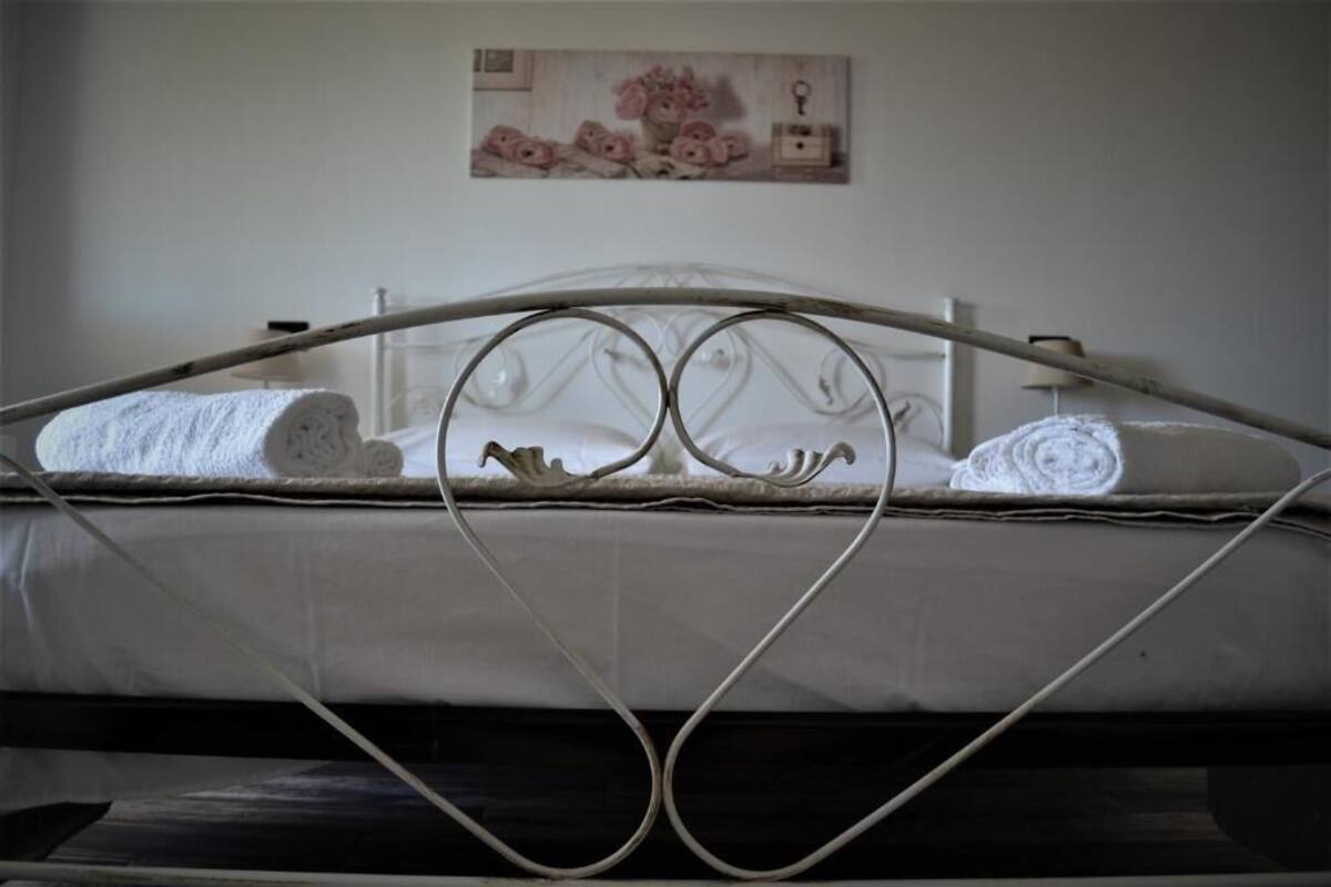 A bed with a metal frame, white bedding, and a wall-mounted picture of flowers.