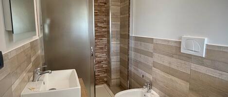 Un baño moderno con ducha, dos lavamanos, un bidé y un inodoro.