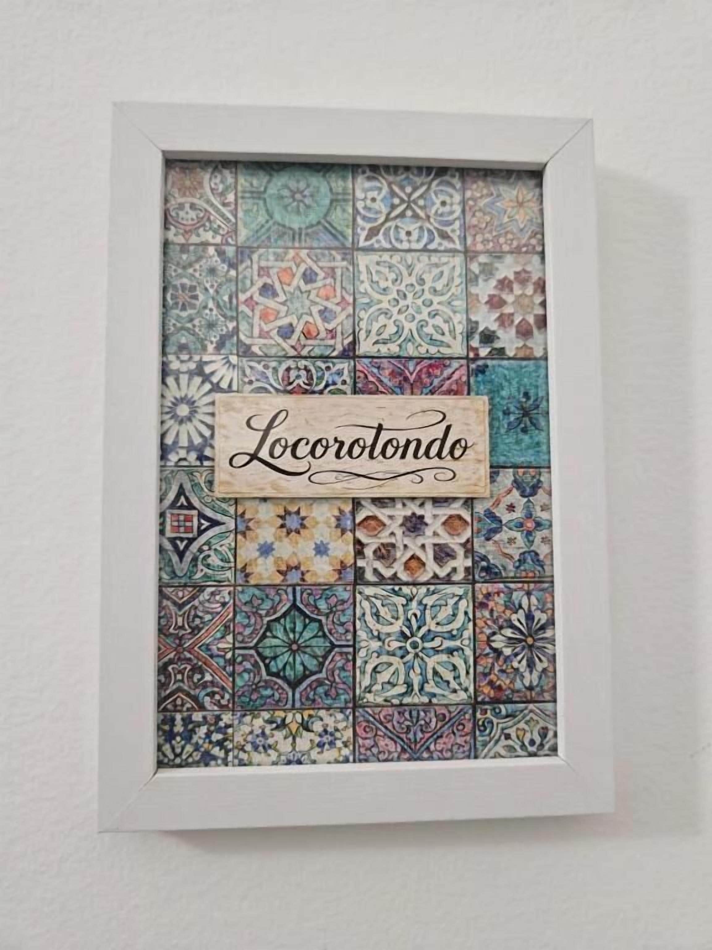Een lijst met een tegelmozaïek waarop de tekst 'Locorotondo' staat, met een bijschrift.
