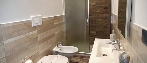 Une salle de bain équipée d’une douche, de toilettes, d’un bidet et d’un lavabo.