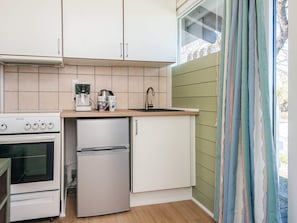 A compact kitchen with a stove, refrigerator, and sink. - 2 Person Holiday Home in Aabenraa (Aabenraa)