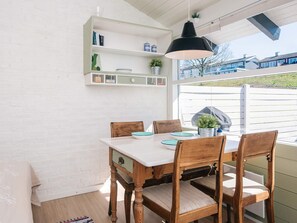 En matplats med ett vitt bord, trästolar och en hängande lampa.