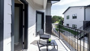 Un balcon avec une chaise, une petite table et un pot de fleurs.