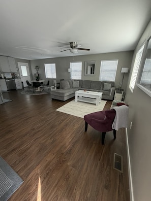 A modern living room with a sectional sofa, a coffee table, and a red armchair. - Your Home Away From Home
Quiet, Modern, & Open 1 (Delta)