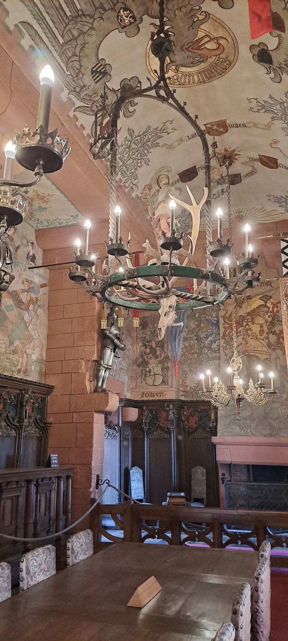 A room with a chandelier, a fireplace, and a mural on the ceiling.