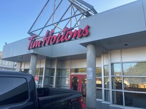 Un negozio Tim Hortons con insegna ben visibile, indicazione di parcheggio e un pick-up nero parcheggiato di fronte.