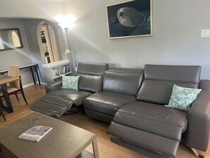 A living room with a grey leather sofa, a wooden coffee table, and a framed picture on the wall. - Vancouver whole home stay with space for extended families & close to everything (Vancouver)