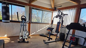 Ein Fitnessstudio mit Trainingsgeräten, einem Sandsack und großen Fenstern.
