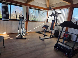 Une salle de sport équipée de matériel d’exercice, d’un sac de frappe et de grandes fenêtres.