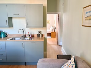 Pieni, käytännöllinen keittiö, jossa on pesuallas, kaappeja ja vedenkeitin.