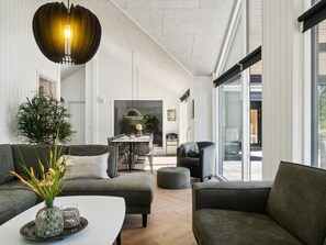 En moderne stue med sofa, skammel og et spiseområde med bord og stole.