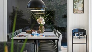 A modern dining area with a large table, chairs, a vase with flowers, and a hanging light fixture. - 5 Star Holiday Home in Hojby (Hojby)