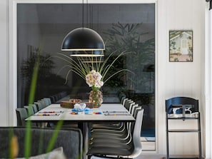 A modern dining area with a large table, chairs, a vase with flowers, and a hanging light fixture. - 5 Star Holiday Home in Hojby (Hojby)