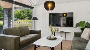 A modern living room with a sofa, a coffee table, a TV, and a pendant light. - 5 Star Holiday Home in Hojby (Hojby)