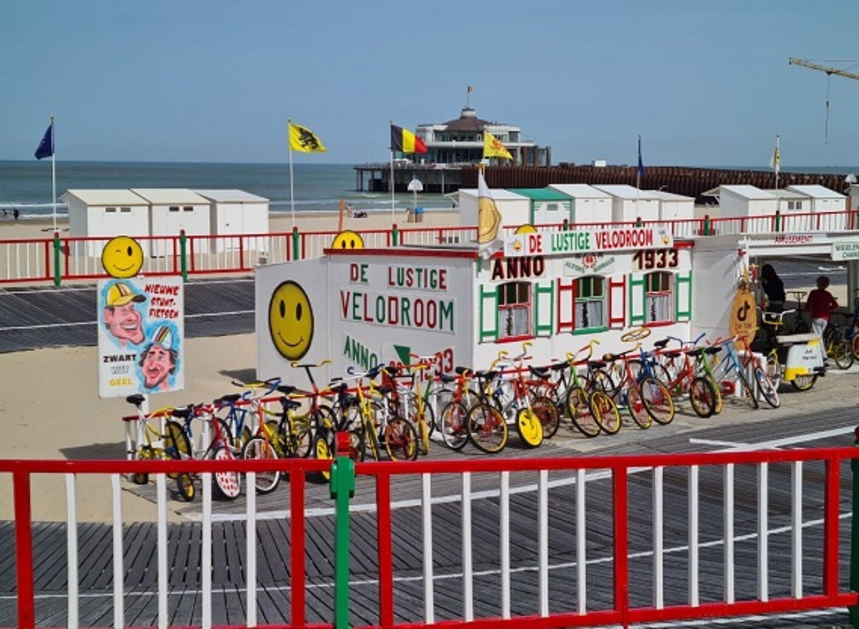 A bicycle rental station with a sign reading "De Lustige Velodroom" and a row of bicycles.