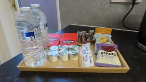 A tray with bottled water, Yorkshire Tea, milk, sugar packets, and chocolate cookies on a kitchen counter.