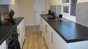 A modern kitchen with a black countertop, stainless steel appliances, and a window providing natural light.
