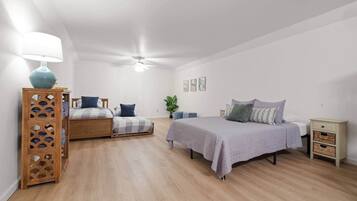 Un dormitorio con dos camas, un ventilador de techo, una mesita de noche de madera y una lámpara fijada a la pared.