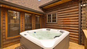Eine Blockhütte mit Whirlpool auf der Terrasse.