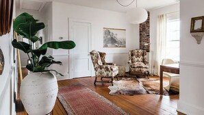 A room with a large white vase, two patterned armchairs, a wooden floor, a hanging light fixture, and a framed picture on the wall. - The Kenwick Pied-à-terre - Lexington Apartment with Historic Charm (Lexington)