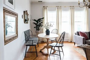 Un coin repas comprenant une table ronde, quatre chaises, une plante en pot et un canapé.