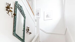 A staircase with white railings and dark steps, leading to a landing with a wall-mounted mirror and wall art. - The Kenwick Pied-à-terre - Lexington Apartment with Historic Charm (Lexington)