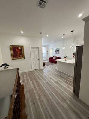 Ein modernes Interieur mit Holzboden, einem roten Sofa und einer Küchenzeile mit Kühlschrank.