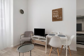 A modern living room with a TV, seating, a small table, and a kitchen area. - Charming Air-Conditioned Studio in Cannes (Cannes)