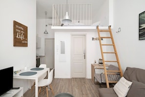 A compact living space with a loft bed, a dining area, a sofa, and a ladder. - Charming Air-Conditioned Studio in Cannes (Cannes)