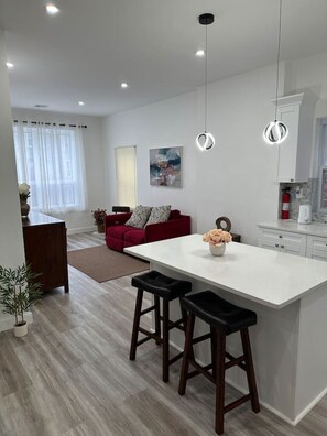 Eine moderne Küche mit einer zentralen Kochinsel, Barhocker, einem roten Sofa und einem Gemälde an der Wand.