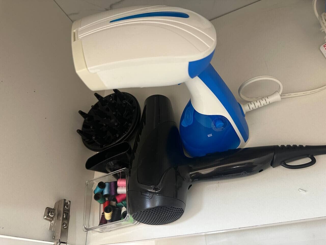 A hairdryer, a blue and white hairbrush, a black hair clip, and a container with hair ties.